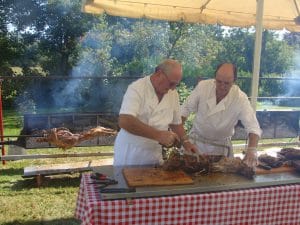 Photographie d’archive de deux personnes préparant de la viande en plein air